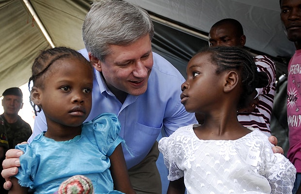 Canada's Prime Minister Stephen Harper (C) greets two Haitian girls